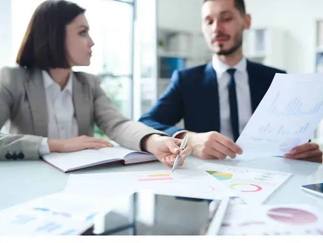 Two people in business attire reviewing charts together