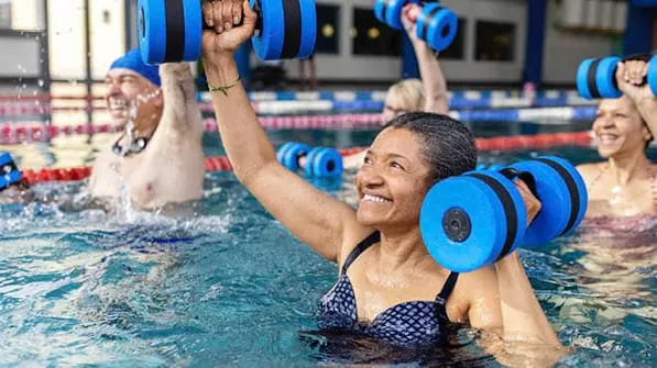 Older adults doing aqua fitness with blue dumbbells in a pool
