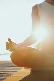 A person seated in meditation at sunrise