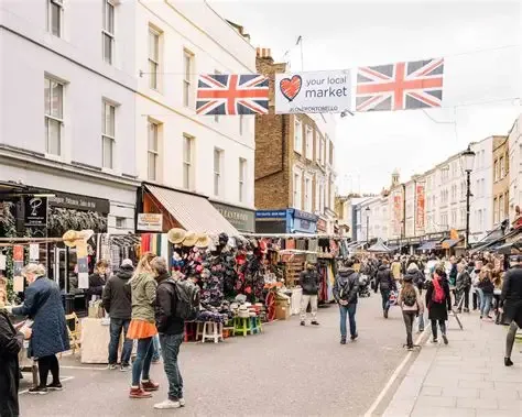 London street market with shoppers, stalls, and Union Jack flags